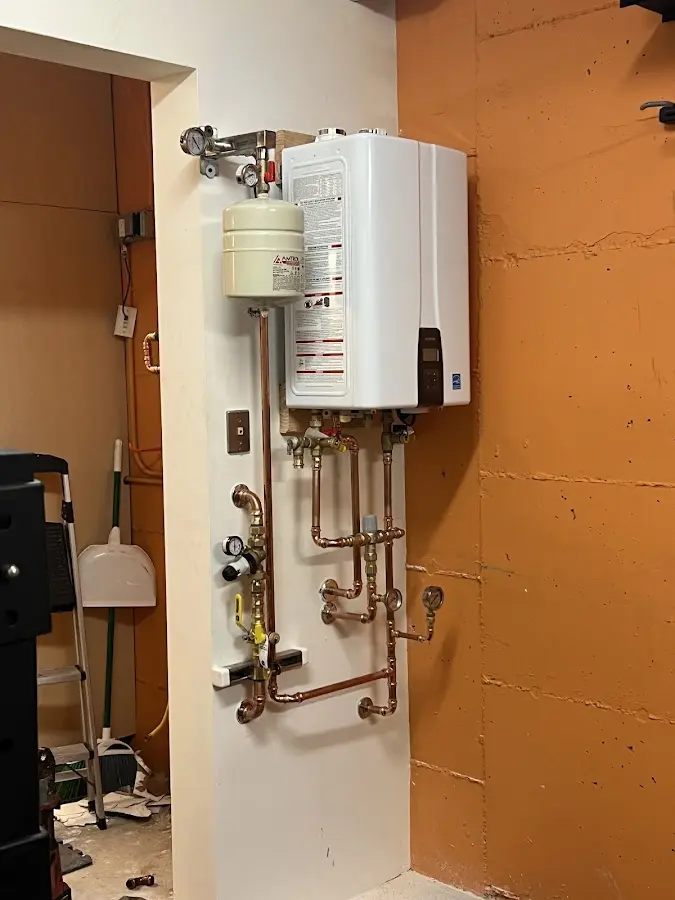 Plumbing technician inspecting water heater connections in St. Anthony